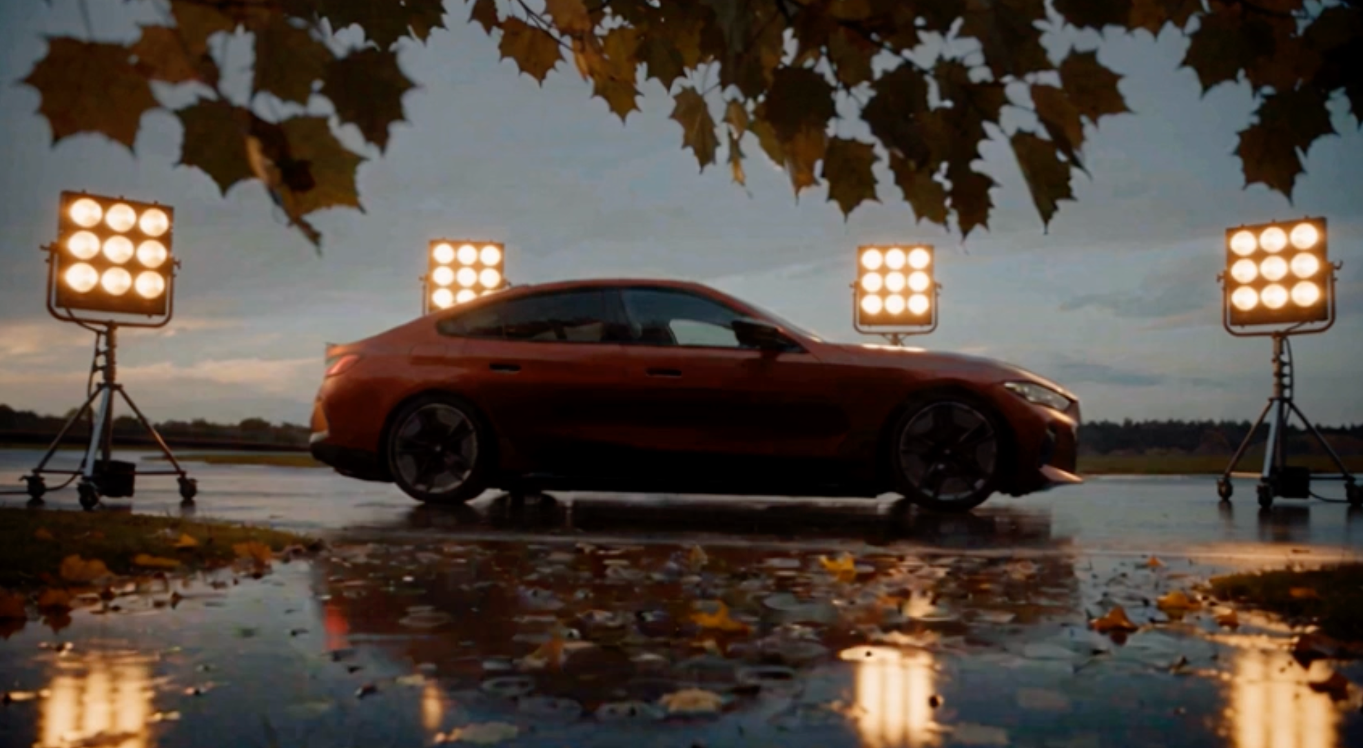 Red electric performance car on a wet track under lights